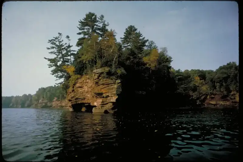 A wooded sandstone island rising from the calm water of Lake Superior