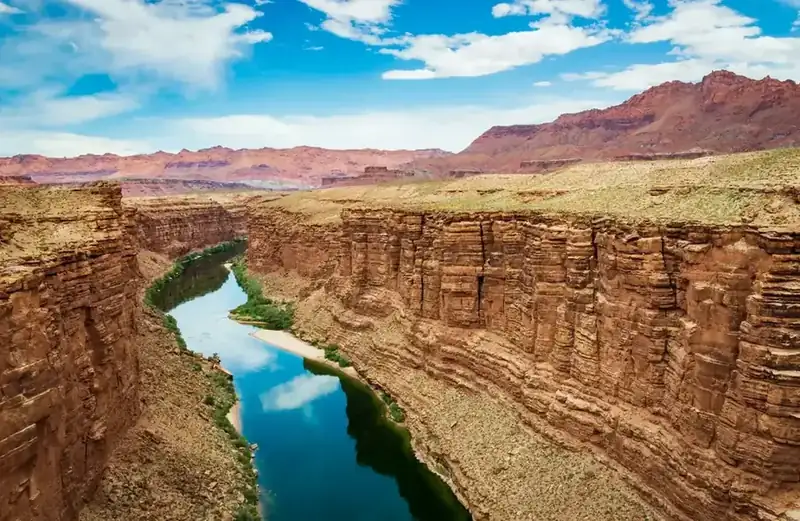 The Colorado River running green between sheer red canyon walls