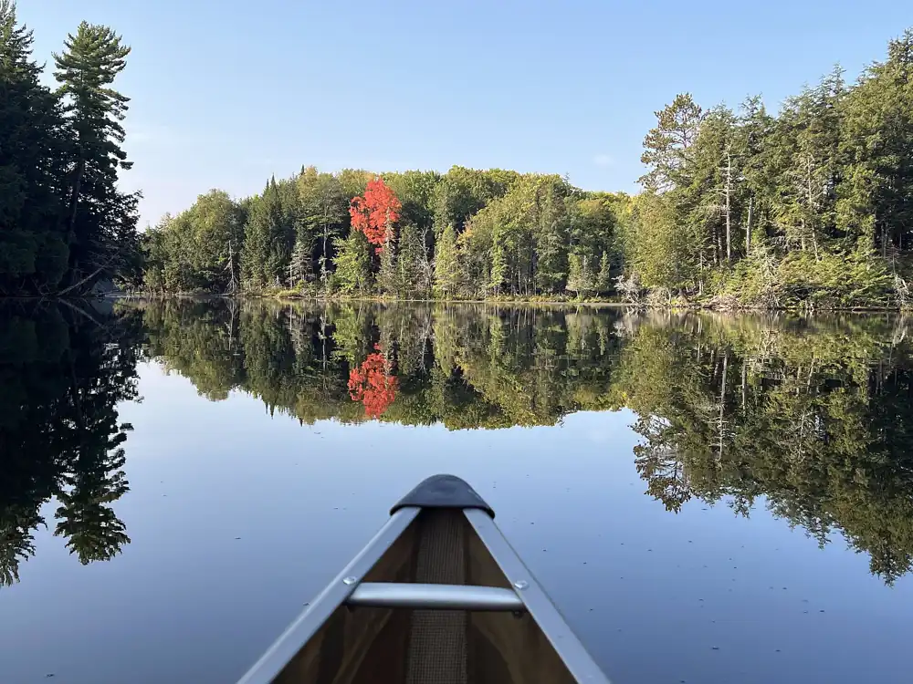 A canoe on a still lake in fall color in the Ottawa National Forest