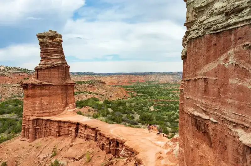 The Lighthouse, a sandstone pillar in Palo Duro Canyon, with hikers on the bench beside it